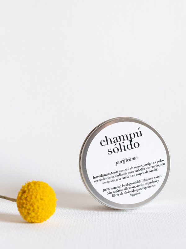 Caja metálica champú sólido purificante junto a un madroño amarillo.